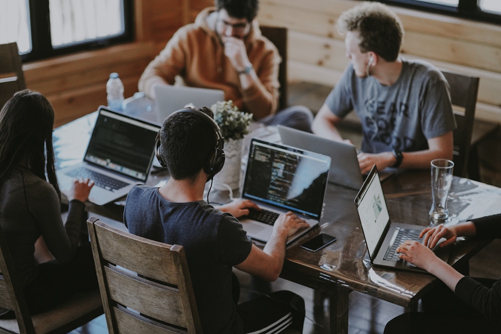 An office team collaborating at a shared table with multiple laptops